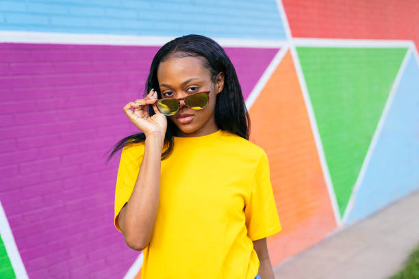 istock Stylish African Woman Lowering Sunglasses Before Colorful Triangle Wall 2002829850