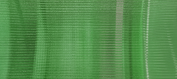 green glass sheet wall or corrugated wall pattern texture use as background. frosted wave glass in horizontal line pattern in the translucent and polished effect.