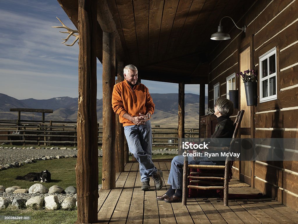 Senior man and woman having conversation on porch, smiling Bozeman, Montana, USA Log Cabin Stock Photo