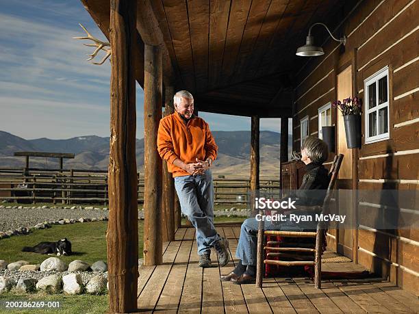 Senior Man And Woman Having Conversation On Porch Smiling Stock Photo - Download Image Now
