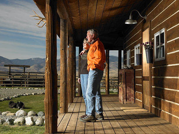 senior homme et femme debout sur le porche, s'enlacer, vue latérale - ranch photos et images de collection