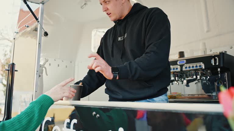 Young Male Food Truck Owner Cleaning Espresso Machine and Serving Coffee Cup to Customer