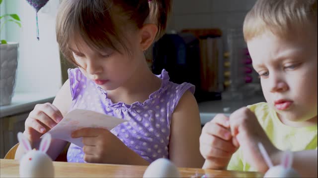 Little girl and boy decorate easter eggs