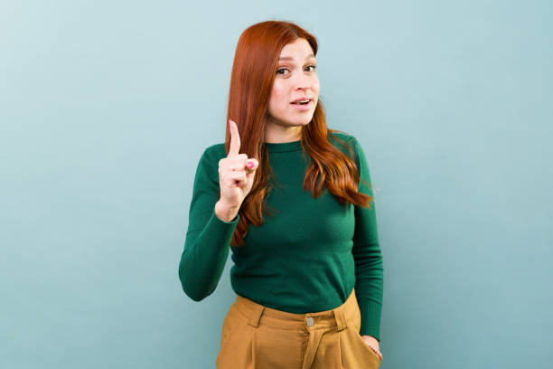 istock Cute Caucasian woman giving some advice and coaching tips while standing in a studio with a blue background 2002935992