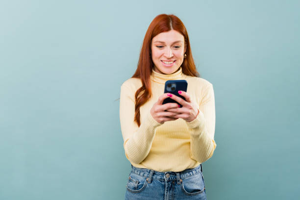 istock Beautiful woman with red hair using her phone texting and smiling 2002942310