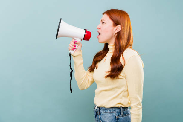 istock Angry redhead woman using a megaphone screaming 2002942838