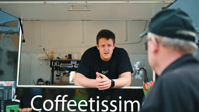 SLO MO Confident Young Coffee Truck Owner Talking with Senior Male Customer