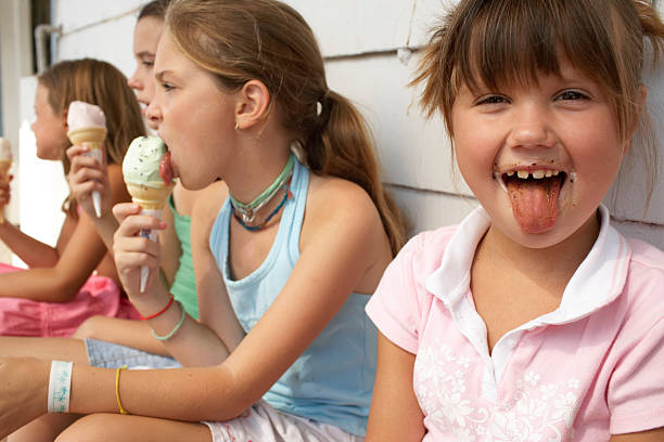 quattro ragazze (6-9) con gelati, un mettere fuori - child chocolate ice cream human mouth foto e immagini stock