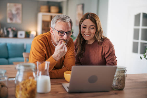 istock Mature couple has breakfast together at home. They enjoy and laugh while talking on a video call. 2002993148