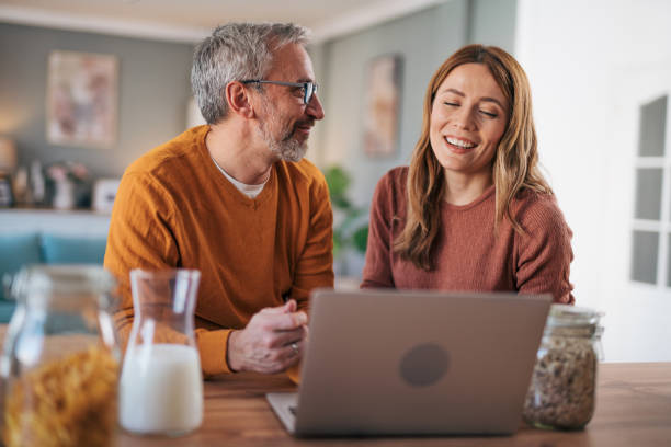 istock Mature couple has breakfast together at home. They enjoy and laugh while talking on a video call. 2003000037