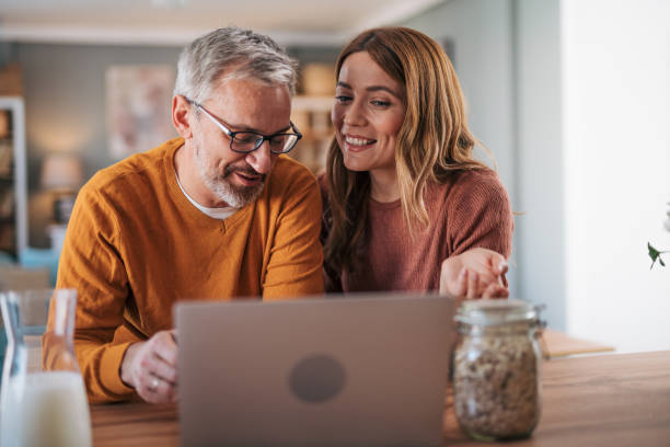 istock Mature couple has breakfast together at home. They enjoy and laugh while talking on a video call. 2003003118