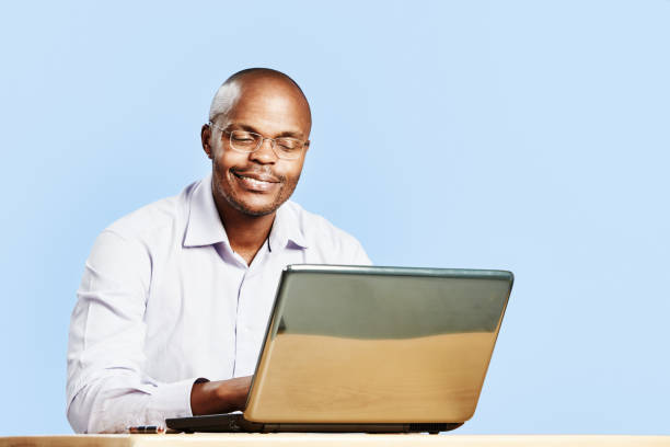 un hombre sonríe enigmáticamente a su computadora portátil - men button down shirt black smug fotografías e imágenes de stock