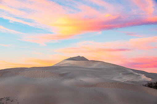 Dry arid desert landscape scene with white sand dunes against a dramatic pink sky. Photographed in Western Australia.