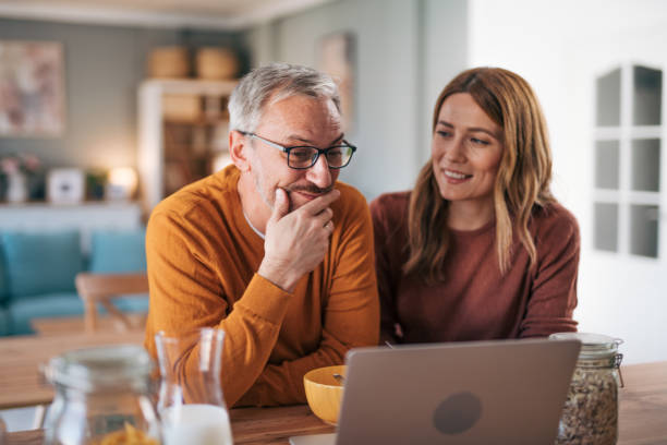 istock Mature couple has breakfast together at home. They enjoy and laugh while talking on a video call. 2003018405