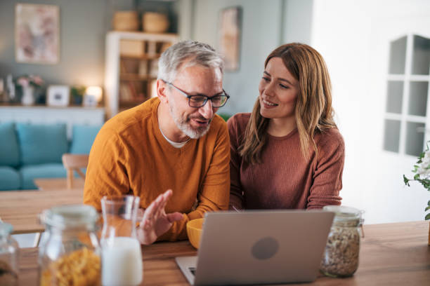 istock Mature couple has breakfast together at home. They enjoy and laugh while talking on a video call. 2003018952