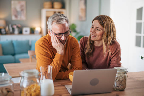 istock Mature couple has breakfast together at home. They enjoy and laugh while talking on a video call. 2003018953