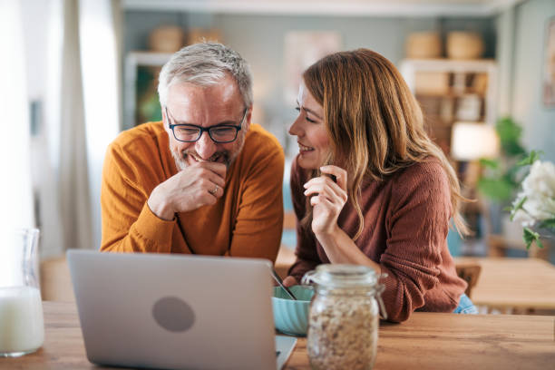 istock Mature couple has breakfast together at home. They enjoy and laugh while talking on a video call. 2003028767