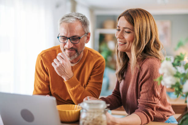 Mature couple has breakfast together at home. They enjoy and laugh while talking on a video call.
