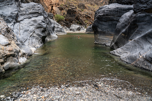 Wadi Bani Awf—one of Oman’s most challenging river gorges, one can swim in winding Snake Gorge. Some women swimming in distance.