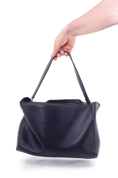 Two stylish black handbags resting on a glass table, reflecting the greenery in the background.