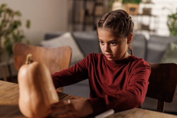 istock Young girl drawing a face on a pumpkin 2003075600