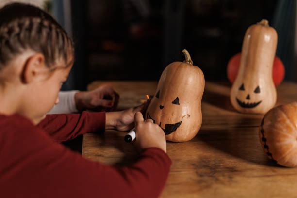 istock Mother and daughter drawing a face on a pumpkin together 2003075771