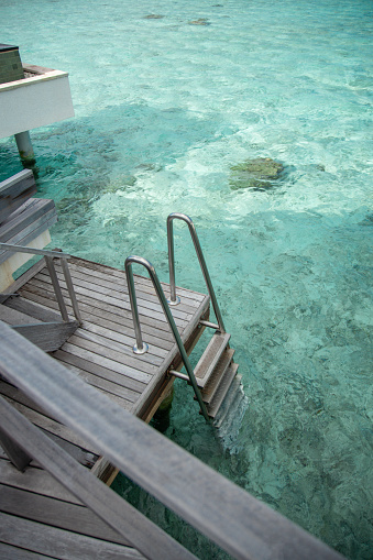 Maldives overwater villa terrace with access step ladder to the sea lagoon at luxury hotel