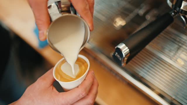 SLO MO Closeup of Male Food Truck Owner Pouring Steamed Milk into Coffee Cup and Makes Latte Art Heart Shape