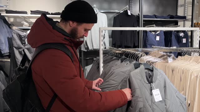 A man chooses jacket in a clothing store
