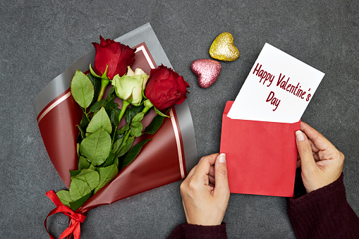 Beautiful roses bouquet flowers with hand holding an envelope with happy  valentine's day