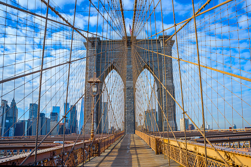 Brooklyn Bridge and New York City Skyline with abstract geometric shapes and lines of the bridge cables against the blue sky with cumulus clouds