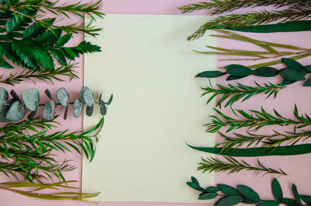 istock Flatlay on light cold pink background, mockup copyspace white sheet of paper both sides framed by herbal twigs and leaves for logo, text or wedding monogram invitation 2003171483