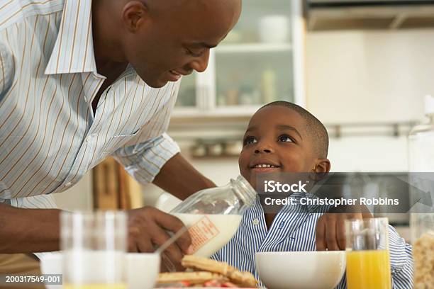 Padre Versare Il Latte Nella Ciotola Di Son Per La Prima Colazione - Fotografie stock e altre immagini di Prima colazione