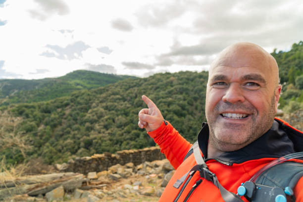istock Hiker takes a selfie pointing with fingers the mountain on background. 2003183556