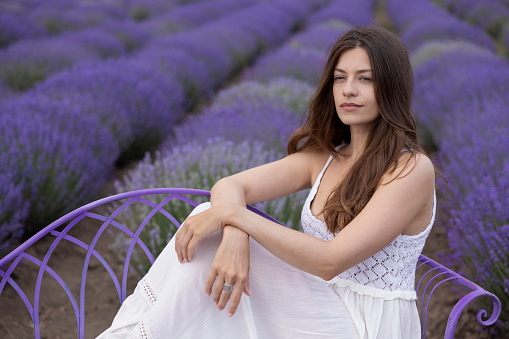 Portrait of a young lovely woman posing in a lavender field with grace.