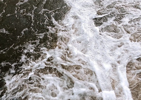The surface of the water with small foaming waves and ripples. A natural photograph of a pond, river or stream in an elegant vintage motif.