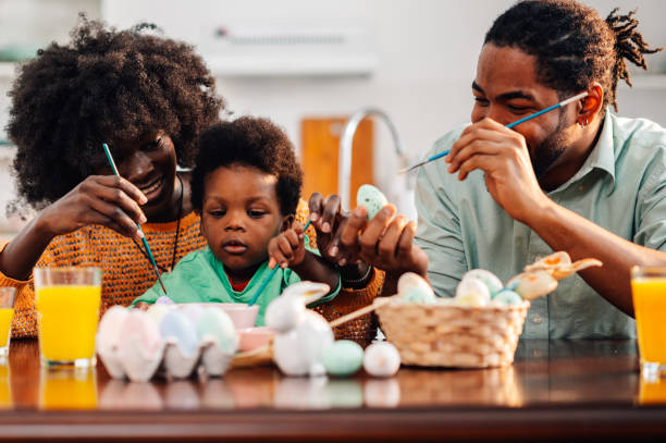 istock Happy multicultural family is painting easter eggs at home together. 2003237271