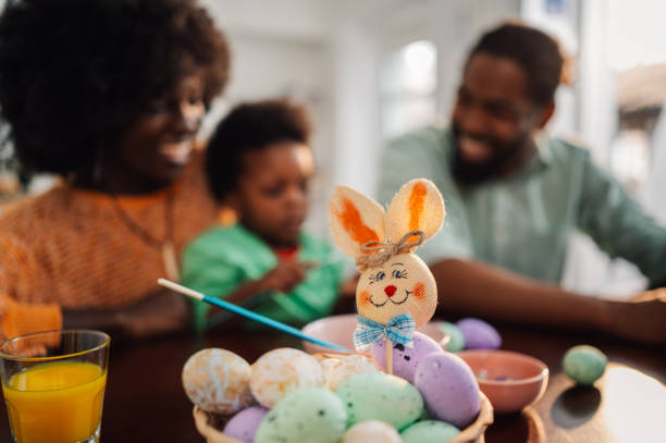 Easter decorations on a table while african american family is painting eggs