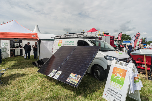 Nantwich, Cheshire, England, July 26th 2023. Solar panels with a white van in the background at a country fair display, energy editorial illustration.