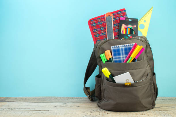 backpack with different colorful stationery on table. light blue background. back to school. - yeni öğretim yılı stok fotoğraflar ve resimler