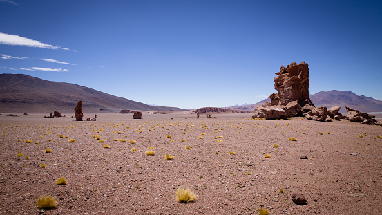 Huge rocks rise up on a flat plain of red sand in the Atacama Desert, the so-called Monjes de Pacana