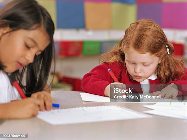 Dos Schoolgirls Dibujo En La Mesa Foto de stock y más banco de imágenes de Instrumento de escribir con tinta - Instrumento de escribir con tinta, Papel, Salón de clase