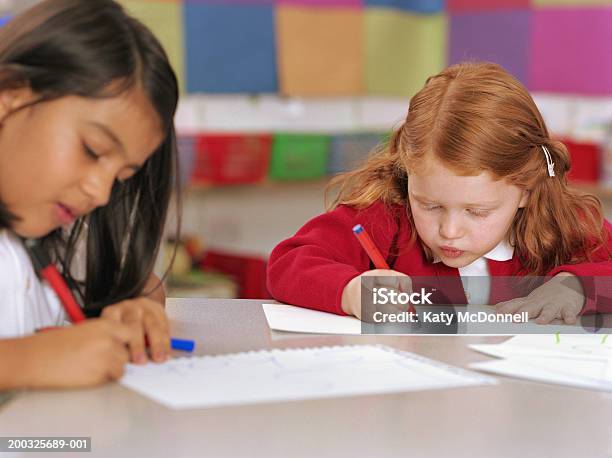 Due Schoolgirls Disegno Al Tavolo - Fotografie stock e altre immagini di Aula - Aula, Carta, Penna