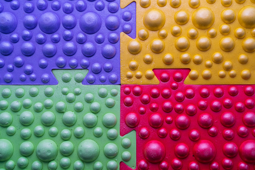 Close-up of a massage mat with round ridges. Multi-colored elements are fastened together like puzzles. Background.