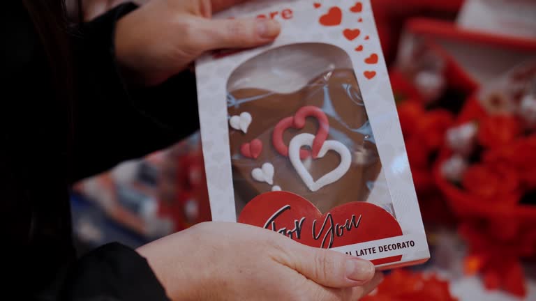 Sale for Valentine's Day. close-up. little box with chocolate gingerbread cookies in the shape of hearts, in hands. Gifts for Valentine's day, as an expression of feelings and love. Shopping in the supermarket for Valentine's Day