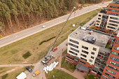 Drone photography of crane removing construction material from the roof during autumn day
