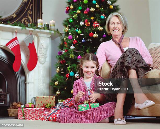 Photo libre de droit de Filles Assis Par Grandmère Tenant Présents Souriant Port banque d'images et plus d'images libres de droit de 50-54 ans