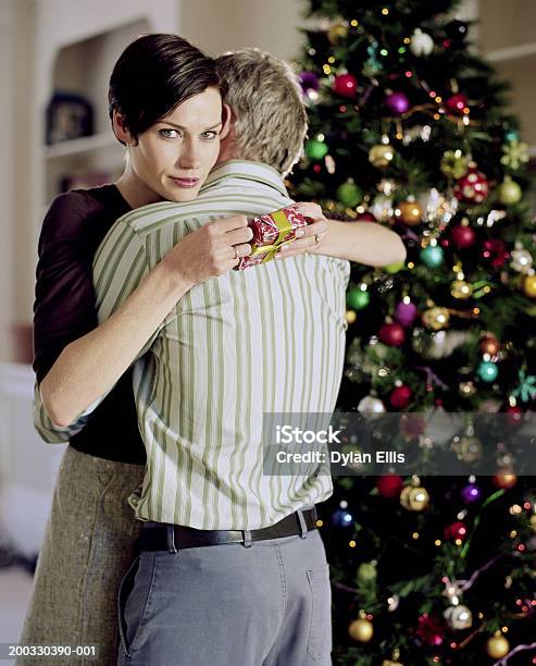 Photo libre de droit de Couple Embrassant Et Femme Tenant Portrait Cadeau De Noël banque d'images et plus d'images libres de droit de Cadeau