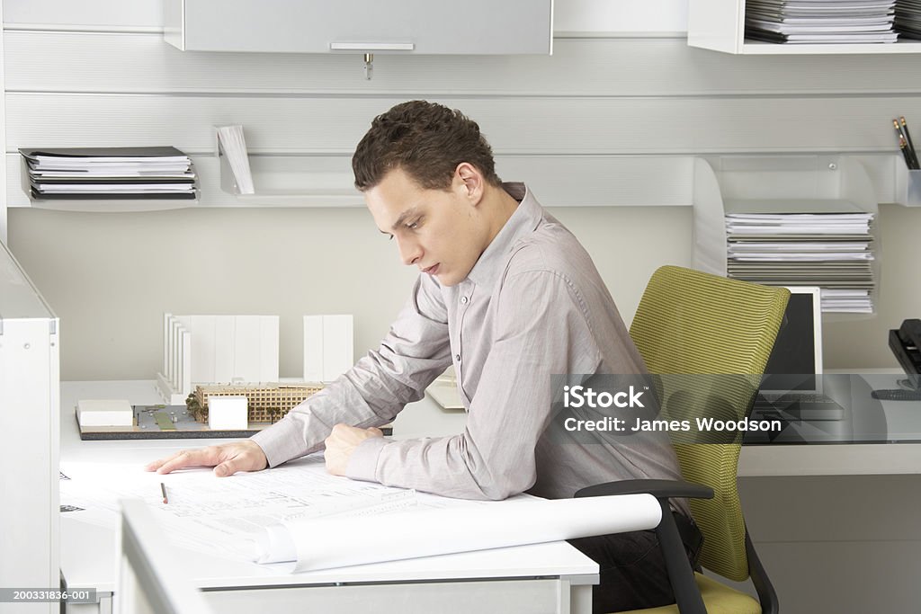 Young businessman looking at blue imprime en escritorio - Foto de stock de 20 a 29 años libre de derechos