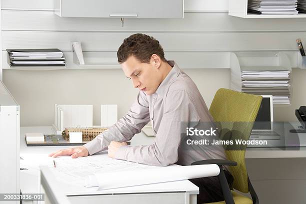 Foto de Jovem Empresário Olhando No Blue Impressões Sobre Uma Escrivaninha e mais fotos de stock de 20 Anos
